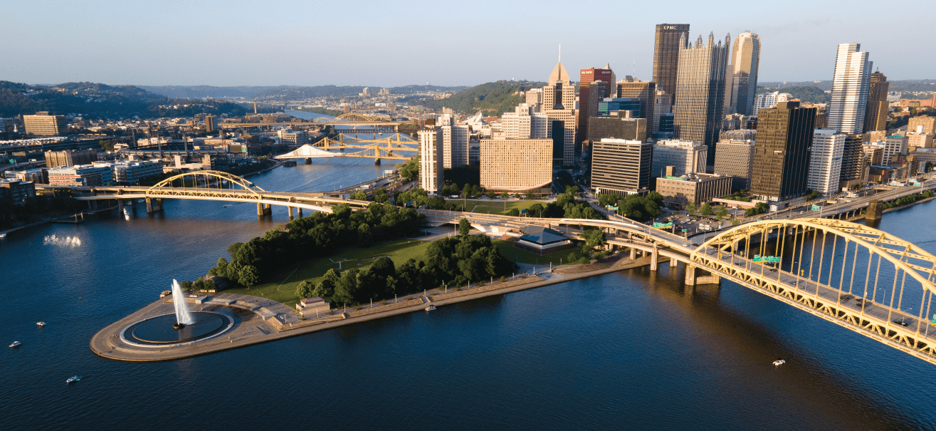 the pittsburgh skyline and the point. two yellow bridges connect to the city from the left and right.