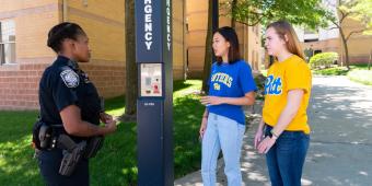 a pitt police officer talks to two members of the pitt community